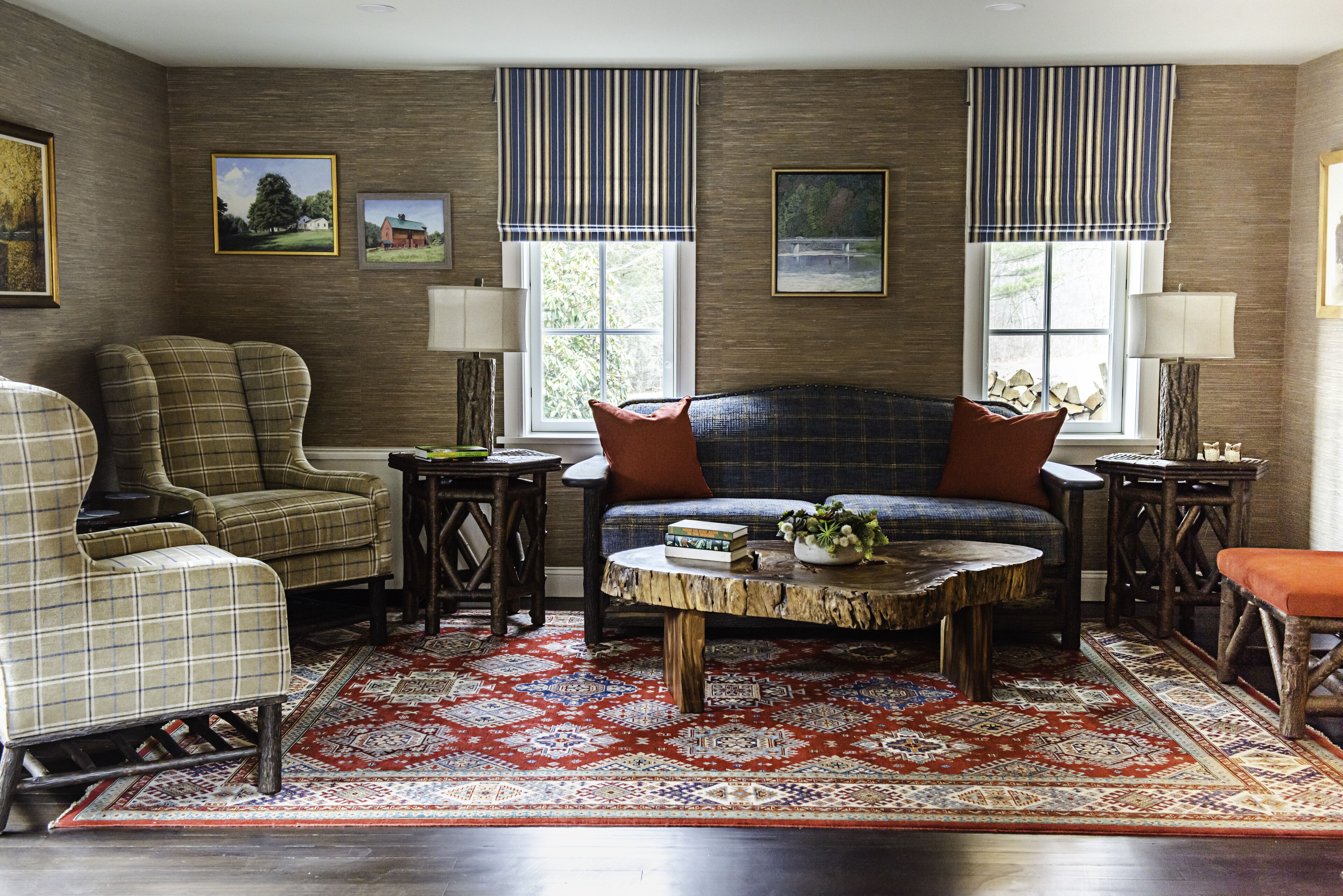 A living room with a plaid sofa, armchairs, a round coffee table, and a patterned rug.