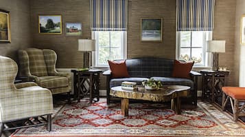 A living room with a plaid sofa, armchairs, a round coffee table, and a patterned rug.