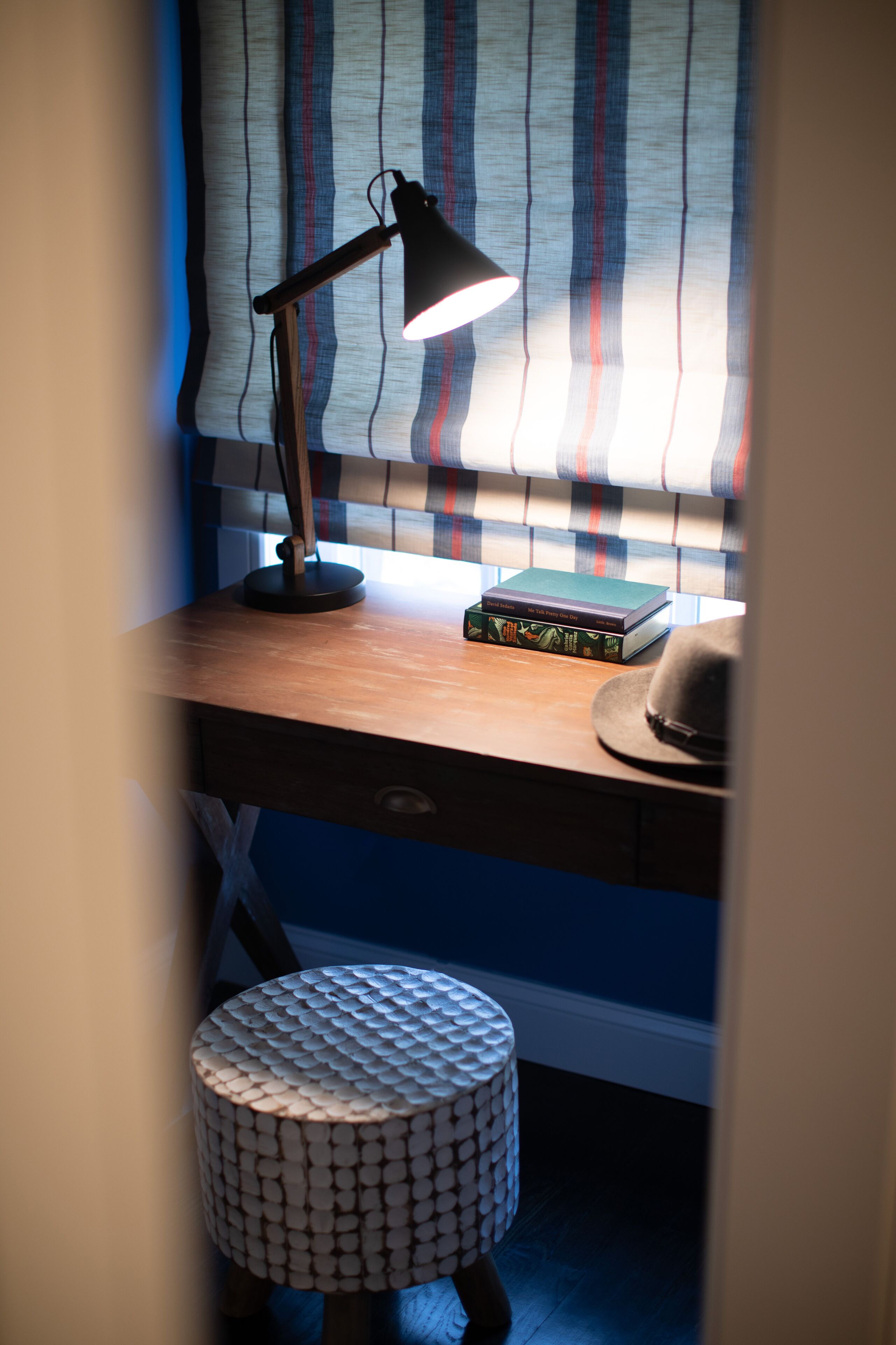 A desk with a lamp, a hat, and books.