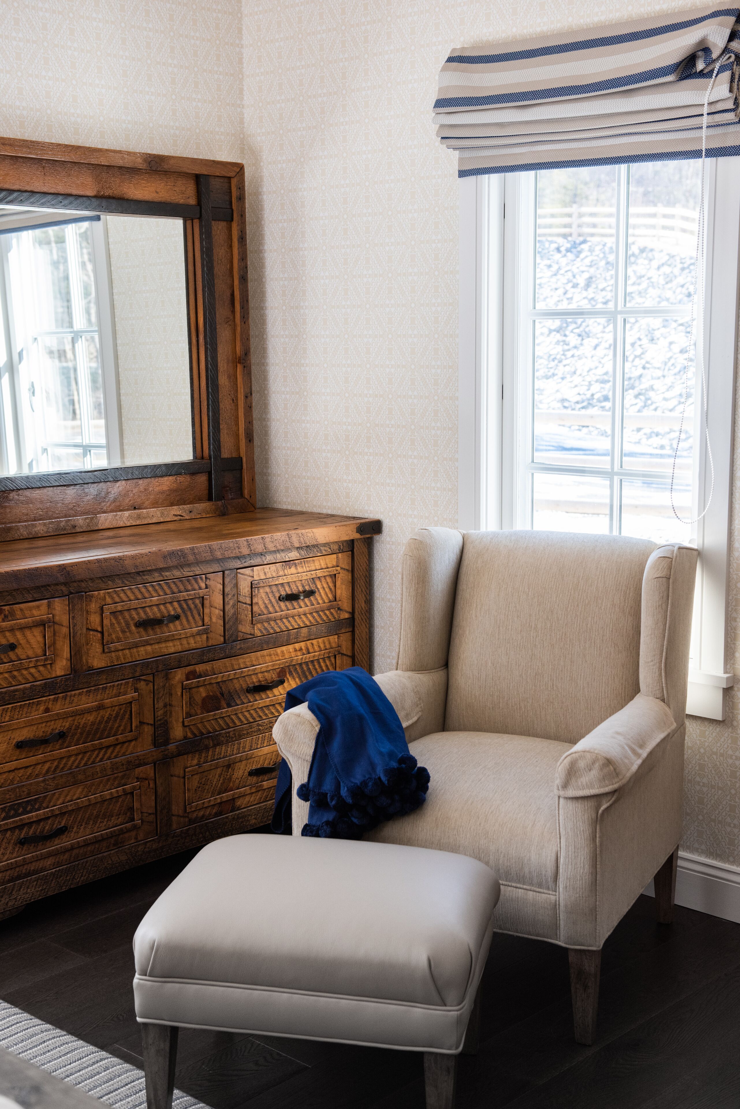 A room with a wooden dresser, a beige armchair, and a white bench.