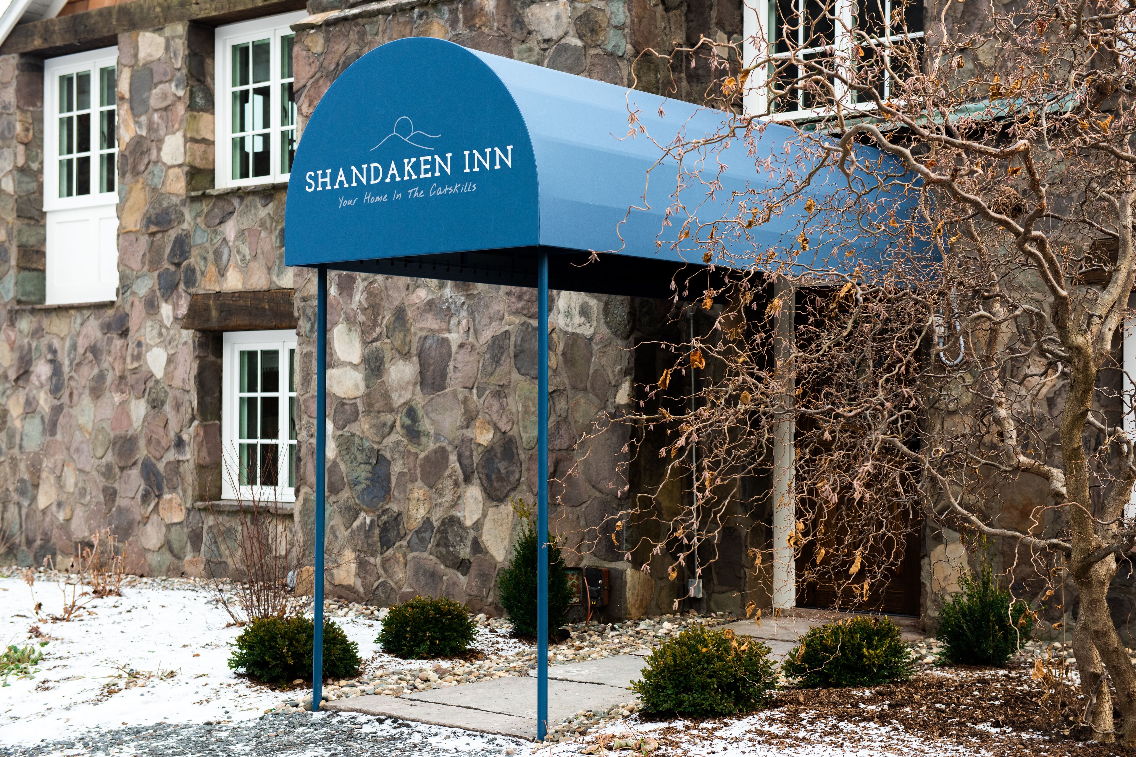 Ein Steinhaus mit einer blauen Markise, auf der 