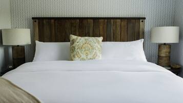 A neatly made bed with white linens and a patterned pillow, flanked by two bedside lamps on wooden nightstands.