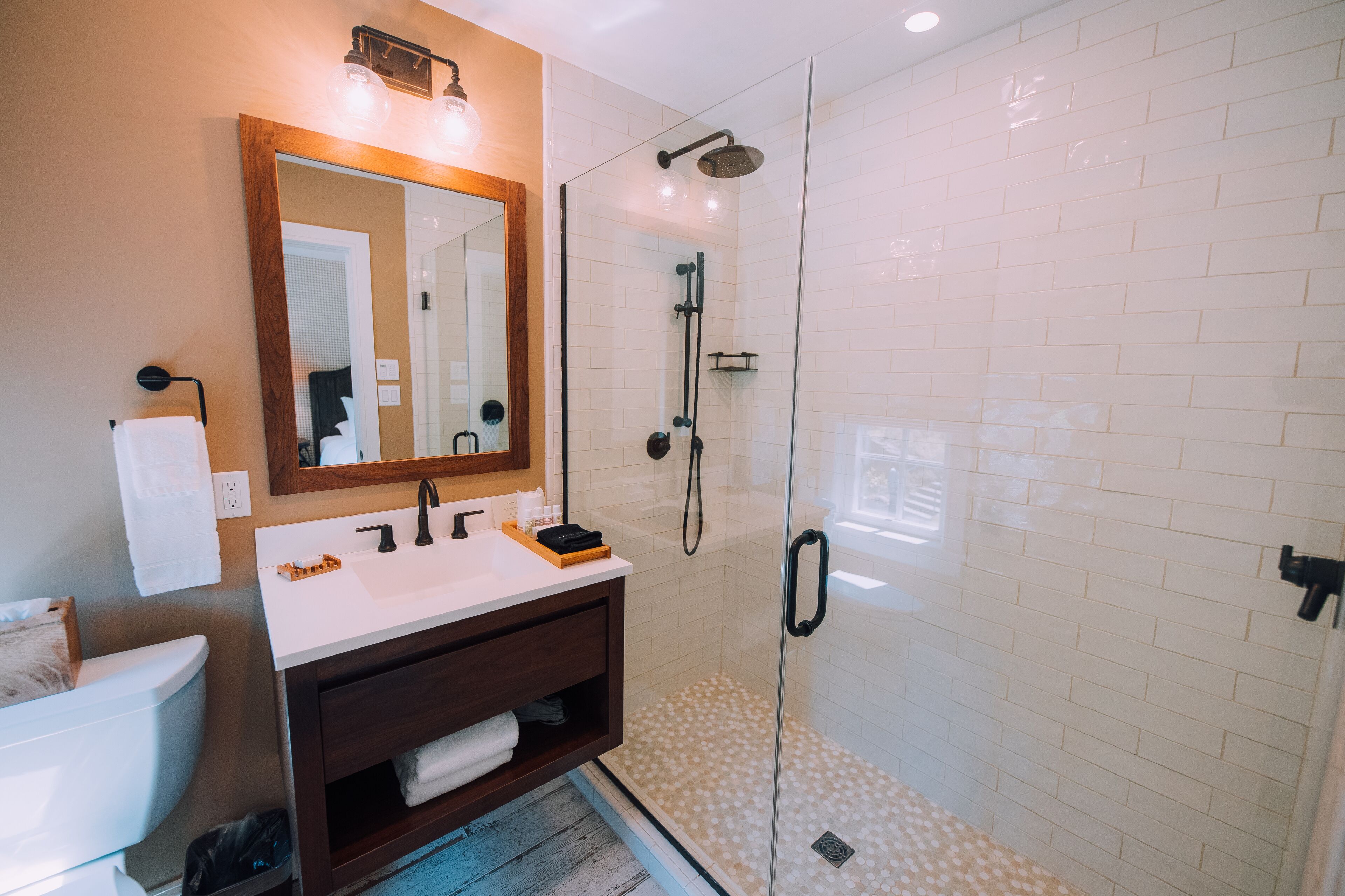 A modern bathroom with a glass-enclosed shower, a white sink, and a wooden vanity.