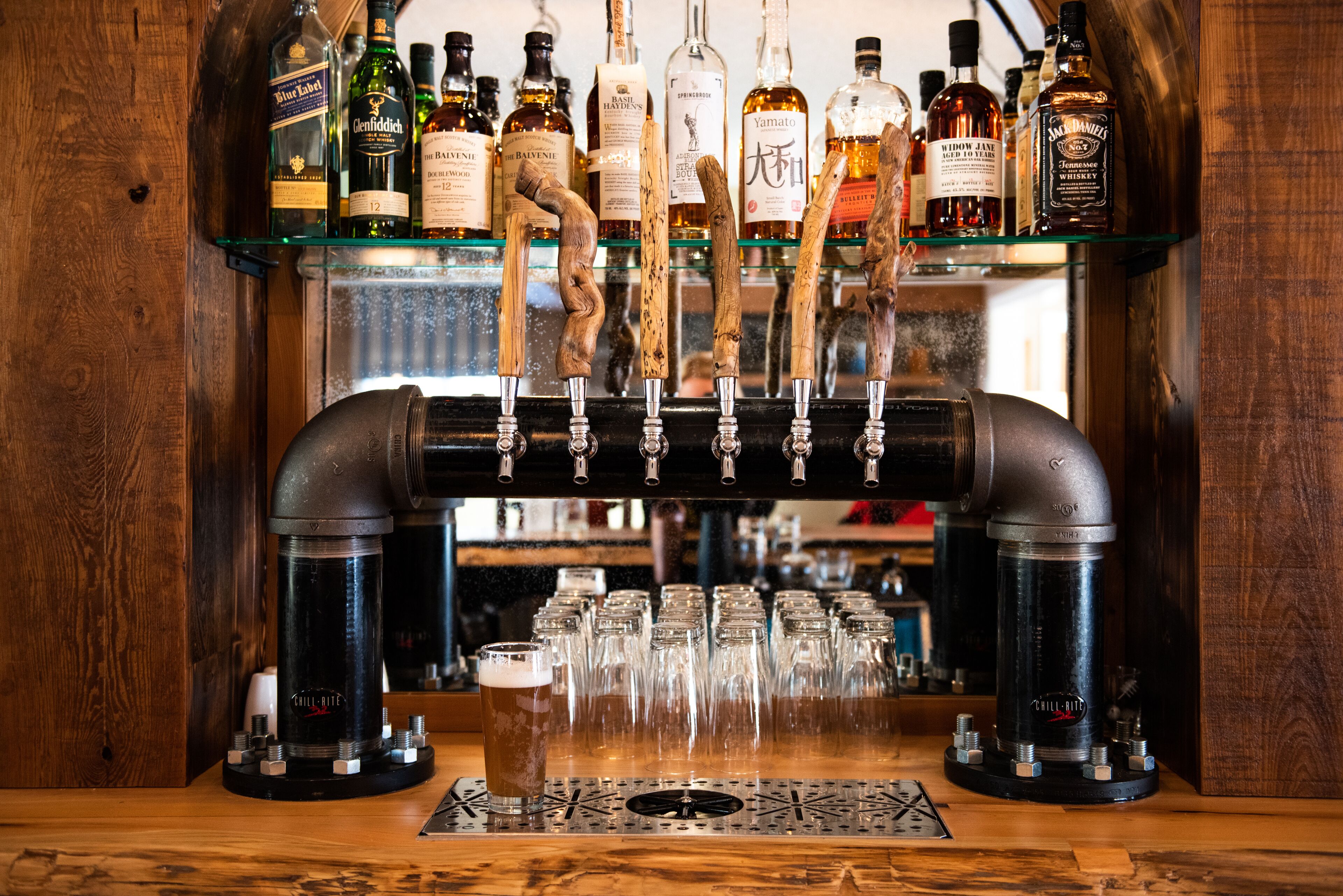 Un bar équipé d’un système de tirage à la pression et proposant une variété de bouteilles d’alcool.