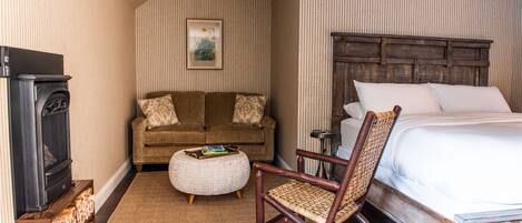 Una habitación de hotel con cama, sofá, sillón, mesita y chimenea.