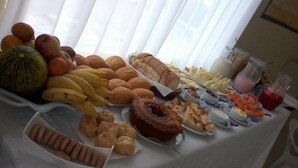 Una mesa de buffet con diversos alimentos, entre ellos frutas, pasteles y postres.