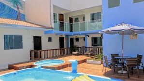 Un hotel con piscina en la azotea, mobiliario exterior y un mural de una palmera.