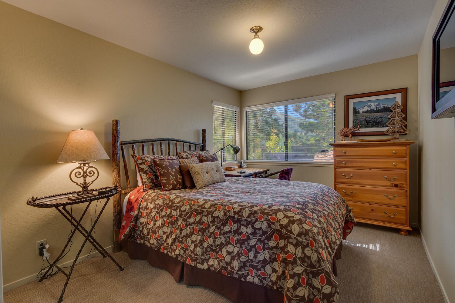 Une chambre à coucher avec un lit, une commode, une lampe et une fenêtre avec des stores.