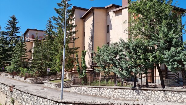 Un immeuble résidentiel dot é de nombreux balcons, de murs en pierre et surplombant un ciel d’un bleu éclatant.
