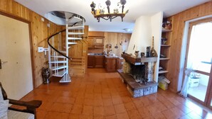 Une cuisine spacieuse avec un escalier en colimaçon, des meubles en bois et une cheminée en pierre.