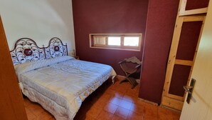 Une chambre à coucher avec un lit, une fenêtre, une chaise et une porte en bois.