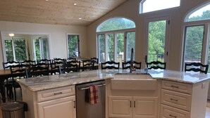 A spacious kitchen with a large island, white cabinetry, and a wooden ceiling.