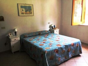 Une chambre à coucher avec un lit, une table de chevet, une lampe et une fenêtre donnant sur un beau paysage.