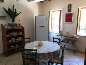 Une petite cuisine avec une table ronde, des chaises, un réfrigérateur et une fenêtre donnant sur un beau paysage.