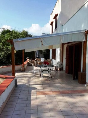 Un patio couvert comprenant une table et des chaises, un canapé et une structure en forme de pergola.