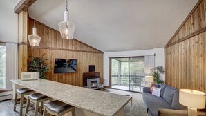 Une cuisine moderne avec un coin bar, des murs en bois, un téléviseur à écran plat et une cheminée.