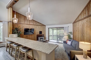 Una cocina moderna con barra, paredes de madera, televisor de pantalla plana y chimenea.
