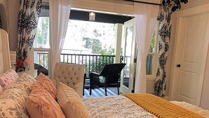 A bedroom with a bed, a chair, and a balcony.