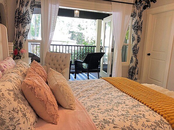 A bedroom with a bed, a chair, and a balcony.