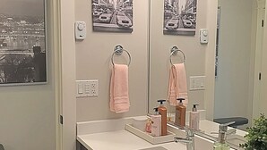 A bathroom with a large mirror, two sinks, a toilet, and a window with a cityscape view.