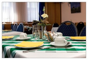 A dining table set with plates, cups, and cutlery, a vase with a white rose, and a salt and pepper shaker. - Zum kleinen Reichstag (Moers)