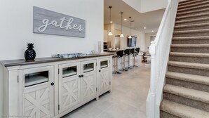 A modern kitchen with a white cabinetry, a wooden countertop, and a 'gather' sign on the wall. - Luxury and Style! BIG Pool Area and Game Room in Solterra 6br/4.5 Bath #7st564 (Davenport)