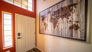 A hallway with a large world map mural, a white door, and a window with blinds. - Goodyear, AZ full home with heated pool and spa and desert oasis back yard!! (Goodyear)