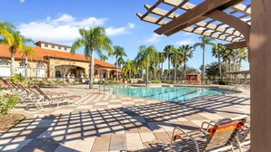 Un espace piscine avec des chaises longues et une pergola.