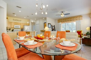 A dining area with a glass table, orange chairs, and a kitchen in the background. - Gorgeous Mediterranean Style Pool/spa Home, Only Minutes From Disneyworld #4wr183 (Davenport)