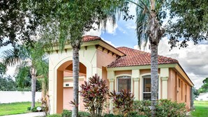 A two-story house with a red-tiled roof, beige walls, and a central archway. - Gorgeous Mediterranean Style Pool/spa Home, Only Minutes From Disneyworld #4wr183 (Davenport)