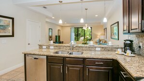 A modern kitchen with granite countertops, stainless steel sink, and dark wooden cabinets. - Championsgate Town Home Near Top Golf Courses and Disney - 3bd/2.5 Bath #3213 (Davenport)