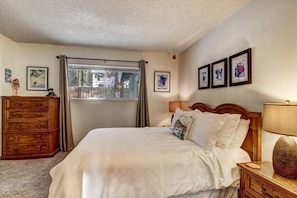 Ein Schlafzimmer mit Bett, Schminktisch, Fenster und Bildern an der Wand.