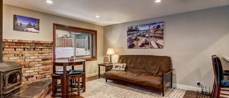 A cozy living room with a fireplace, a sofa, a dining table, and artwork on the walls.