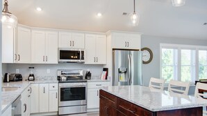 Una cocina moderna con armarios blancos, electrodomésticos de acero inoxidable, una encimera de granito y una isla grande.