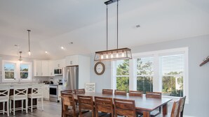 Una cocina moderna con armarios blancos, una mesa de comedor de madera y una lámpara colgante.