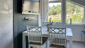 Un coin repas avec deux chaises blanches, une table et un téléviseur fixé au mur.