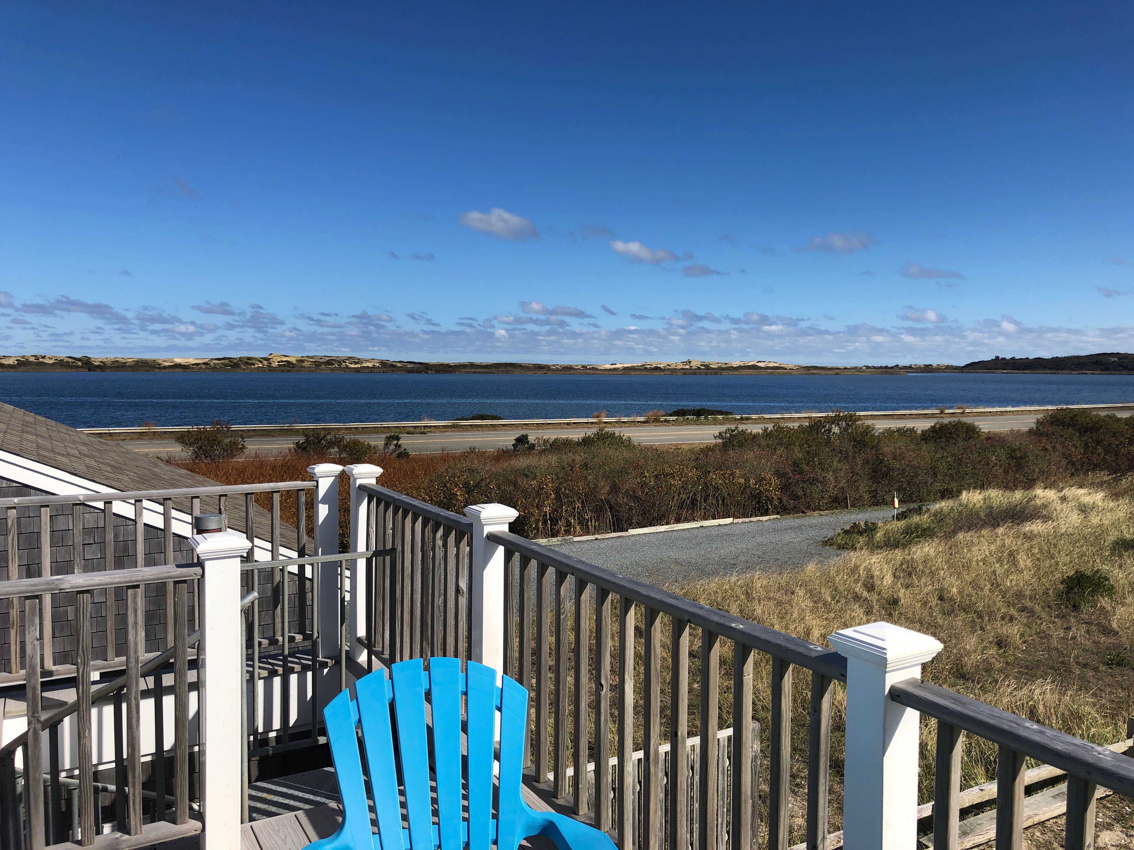 A wooden staircase with a blue chair, leading to a view of a body of water and distant land.
