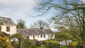 A white cottage with a stone wall and a wooden fence. - 1 bedroom accommodation in Llangennith, near Swansea (Llangennith, near Swansea)