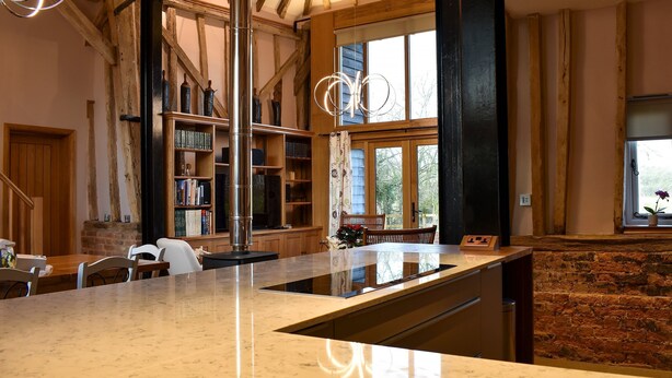 A spacious kitchen with a large island, wooden beams, and a brick wall. - 3 bedroom accommodation in Ashdon, near Saffron Walden (Ashdon, near Saffron Walden)