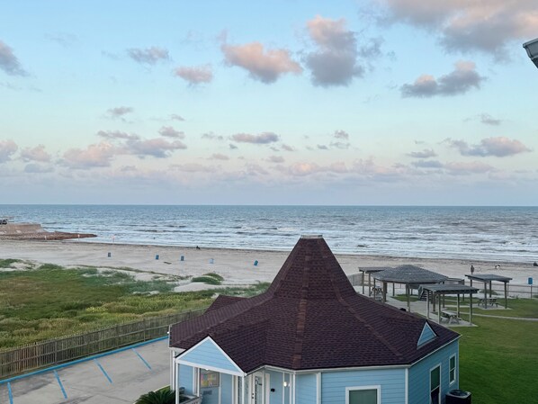 Ein Strandhaus mit geneigtem Dach, einem eingezäunten Garten und Blick auf den Ozean.