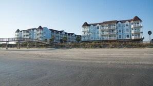 Ein Strandhotel mit mehreren Balkonen und einer Brücke zum Strand.