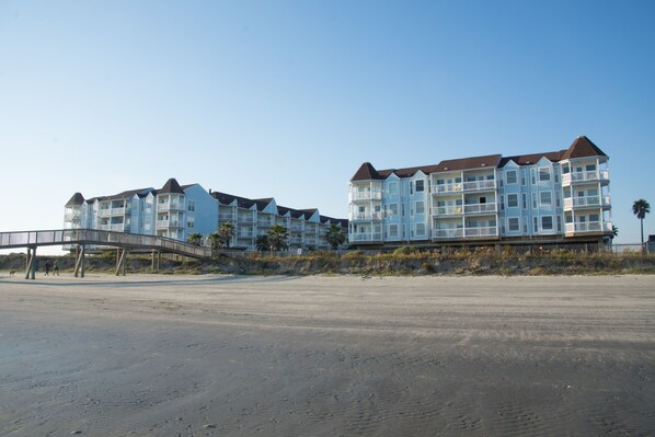 Ein Strandhotel mit mehreren Balkonen und einer Brücke zum Strand.