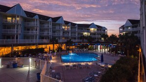 Ein Hotel mit mehreren Balkonen, einem Schwimmbad und Außenbereichs-Sitzgelegenheiten.