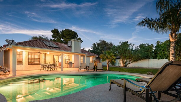 Ein Haus mit Swimmingpool, Gartenmöbeln und einer Terrasse.