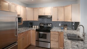 A modern kitchen with wooden cabinets, stainless steel appliances, a granite countertop, and a built-in oven. - Panorama Horsethief Lodge 2 bedroom condo, Sleeps 6: Unit 516 (Panorama)