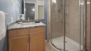 A bathroom with a glass-enclosed shower, a marble countertop, and wooden cabinets. - Panorama Horsethief Lodge 2 bedroom condo, Sleeps 6: Unit 516 (Panorama)