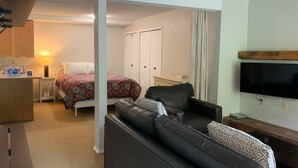 Une chambre d’hôtel comprenant un lit, un canapé, une télévision, un bureau et une armoire.