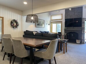 A modern living room with a dark grey sofa, a wooden dining table, and grey upholstered chairs. - Spacious 2 king bdrm + Sleeping Loft + Game Room (Mammoth Lakes)