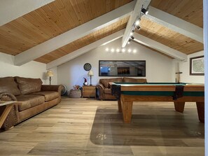 A cozy living room with a pool table, leather sofa, and a dartboard. - Spacious 2 king bdrm + Sleeping Loft + Game Room (Mammoth Lakes)