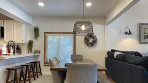 Eine moderne Küche mit Essbereich, ausgestattet mit einem Holztisch, grau gepolsterten Stühlen und einem dunkelgrauen Sofa.